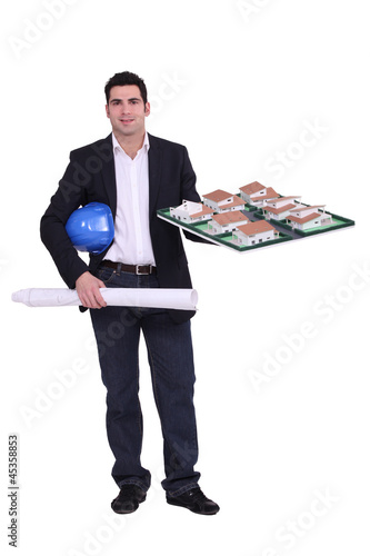 Photo: Architect stood with scale model of housing estate Architect stood with scale model of housing estate