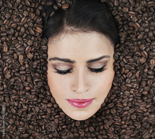 Photo: Beautiful face of brunette among coffe beans Beautiful face of brunette among coffe beans