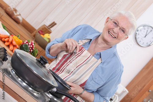 Photo: Old lady cooking in kitchen Old lady cooking in kitchen