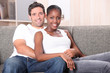 Mixed race couple sat on sofa