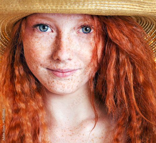 Photo: Beautiful freckled young woman wearing straw hat Beautiful freckled young woman wearing straw hat