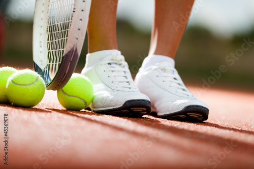 Photo: Legs of athlete near the tennis racket and balls Legs of athlete near the tennis racket and balls