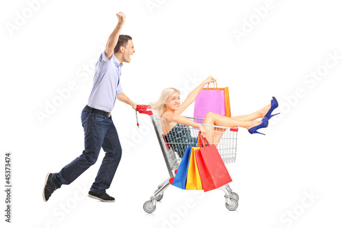 Photo: Excited person pushing a shopping cart, happy woman with bags in Excited person pushing a shopping cart, happy woman with bags in
