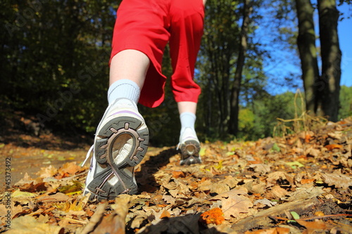 Photo: Woman walking cross country trail in autumn forest Woman walking cross country trail in autumn forest