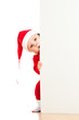 Foto: small Santa claus child looking from behind the placard or banne small Santa claus child looking from behind the placard or banne