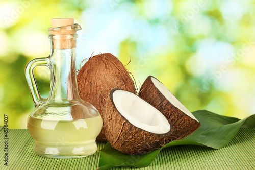 Photo: decanter with coconut oil and coconuts on green background decanter with coconut oil and coconuts on green background