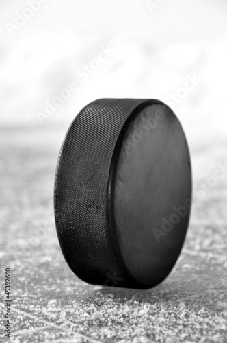 Photo: black hockey puck on ice rink black hockey puck on ice rink