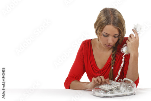 Photo: Junge Frau wählt am Telefon eine Nummer Junge Frau wählt am Telefon eine Nummer