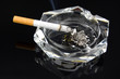 A cigarette in an ashtray against a dark background.
