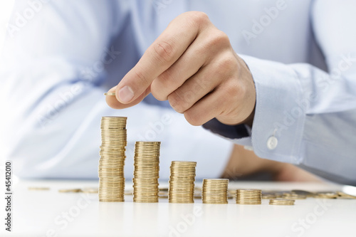 Photo: Savings, male hand stacking gold coins Savings, male hand stacking gold coins