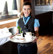 Pretty waitress posing with tea for guests