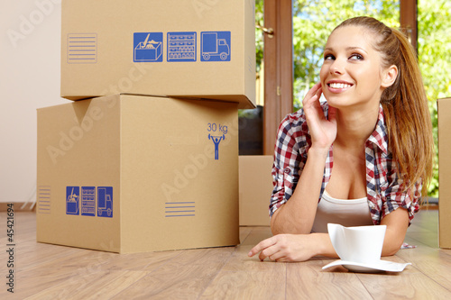 Photo: A beautiful single young woman unpacking boxes and moving into a A beautiful single young woman unpacking boxes and moving into a