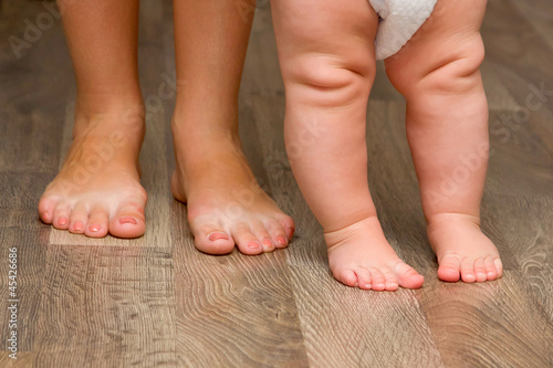 Photo: Legs of mother and baby. First steps. Legs of mother and baby. First steps.