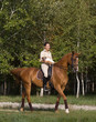 Smiling girl rides a horse with dog