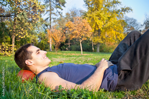 Photo: Young man lying on a meadow grass in park Young man lying on a meadow grass in park