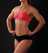muscular female body against black background.