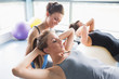 Foto: Female trainer helping woman doing sit-ups Female trainer helping woman doing sit-ups