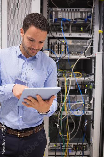 Photo: Man in data centre with tablet pc Man in data centre with tablet pc
