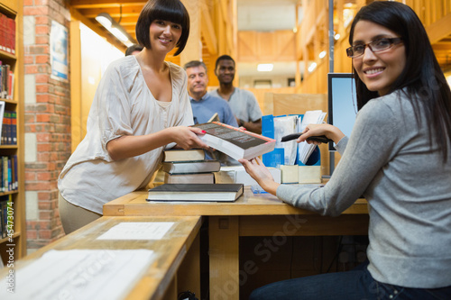 Photo: Librarian scanning book and handing to woman Librarian scanning book and handing to woman