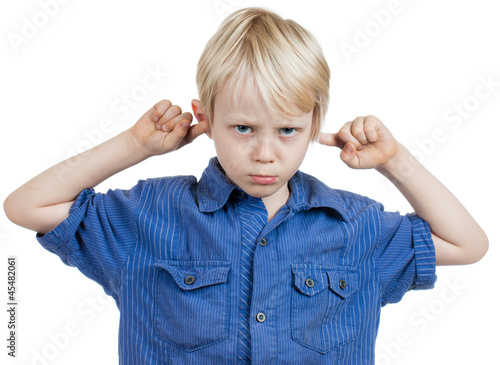 Photo: Grumpy boy covers his ears with fingers Grumpy boy covers his ears with fingers