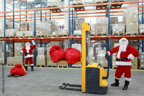 Photo: two santa clauses workers at work in large storehouse two santa clauses workers at work in large storehouse