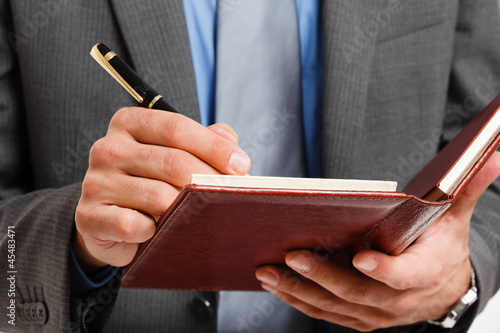 Photo: Businessman writing on his agenda Businessman writing on his agenda