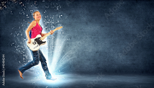 Photo: young woman playing on electro guitar and jumping young woman playing on electro guitar and jumping