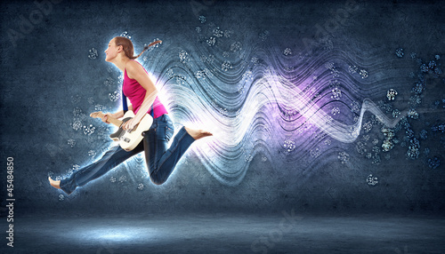 Photo: young woman playing on electro guitar and jumping young woman playing on electro guitar and jumping