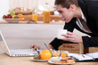Businesswoman looking at a laptop over breakfast