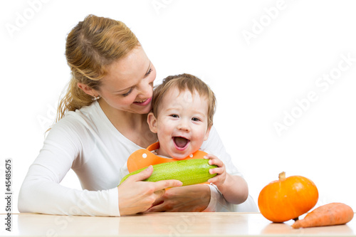 Photo: Mother with baby baby at table. Boy holding zucchini Mother with baby baby at table. Boy holding zucchini