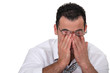 Tired worker rubbing his eyes