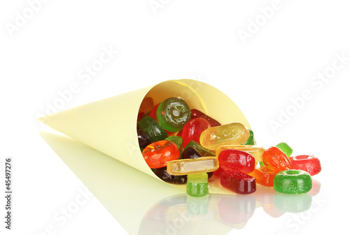 Photo: Tasty colorful candies in bright bag isolated on white Tasty colorful candies in bright bag isolated on white