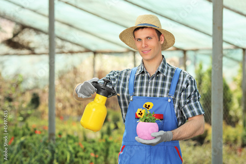 Photo: Male gardener watering a plant in a garden Male gardener watering a plant in a garden