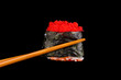 holding sushi with chopsticks isolated on black