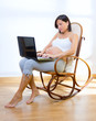 Beautiful pregnant woman at home with laptop