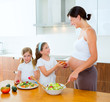 Beautiful pregnant mother with her daughters at kitchen