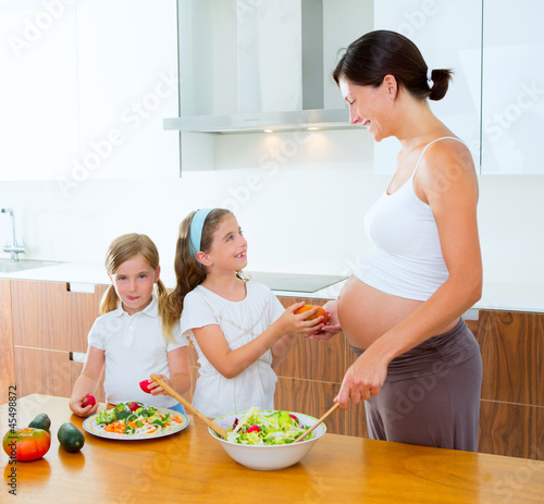 Photo: Beautiful pregnant mother with her daughters at kitchen Beautiful pregnant mother with her daughters at kitchen