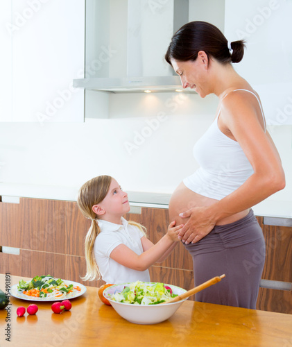 Photo: Beautiful pregnant mother with her daughter at kitchen Beautiful pregnant mother with her daughter at kitchen