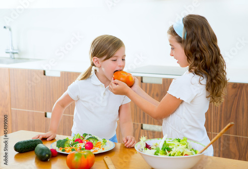 Photo: Beautiful chef sisters at home kitchen preparing salad Beautiful chef sisters at home kitchen preparing salad