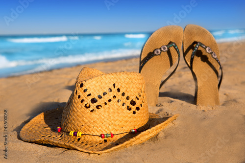 Photo: golden sand beach with summer hat and sandals golden sand beach with summer hat and sandals