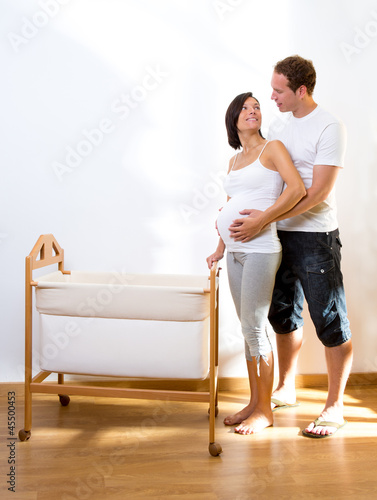 Photo: Couple with pregnant woman hug with baby cradle Couple with pregnant woman hug with baby cradle