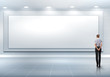 Business person standing near a blank billboard