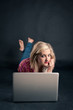 Photo: Pretty girl working on a laptop against black background. Pretty girl working on a laptop against black background.