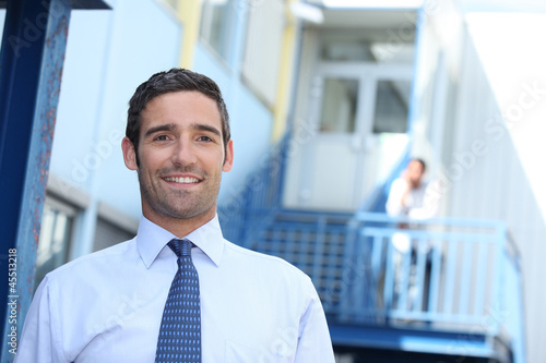 Photo: Businessman standing outside an office building Businessman standing outside an office building