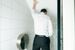 Ein Mann steht in der Toilette und pinkelt