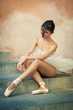 Young beautiful ballerina posing sit on the stairs. 