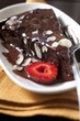 A piece of chocolate cake with chocolate sauce, slivered almonds and strawberries