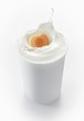 An apricot falling into a cup of yogurt