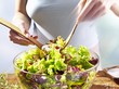 A woman mixing salad in a bowl