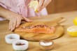 Woman Squeezing a Lemon Wedge over Salmon